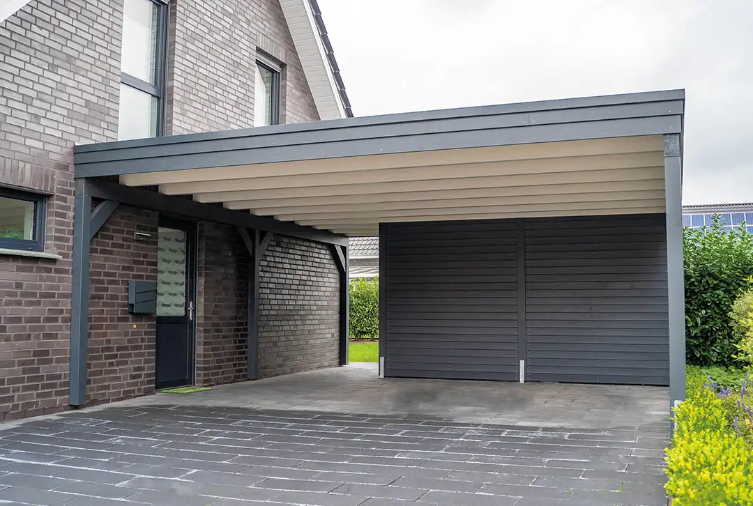 Moderner Carport mit Flachdach aus Metall neben Wohnhaus – maßgefertigte Überdachung für Einfahrt